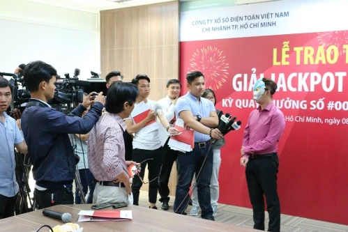 Một người trúng độc đắc Vietlott đeo mặt nạ trả lời báo chí đầu năm 2017.